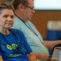 woman smiling as she listens at a professional learning, seated indoors
